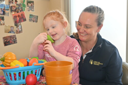 Educator and child with toy fruits